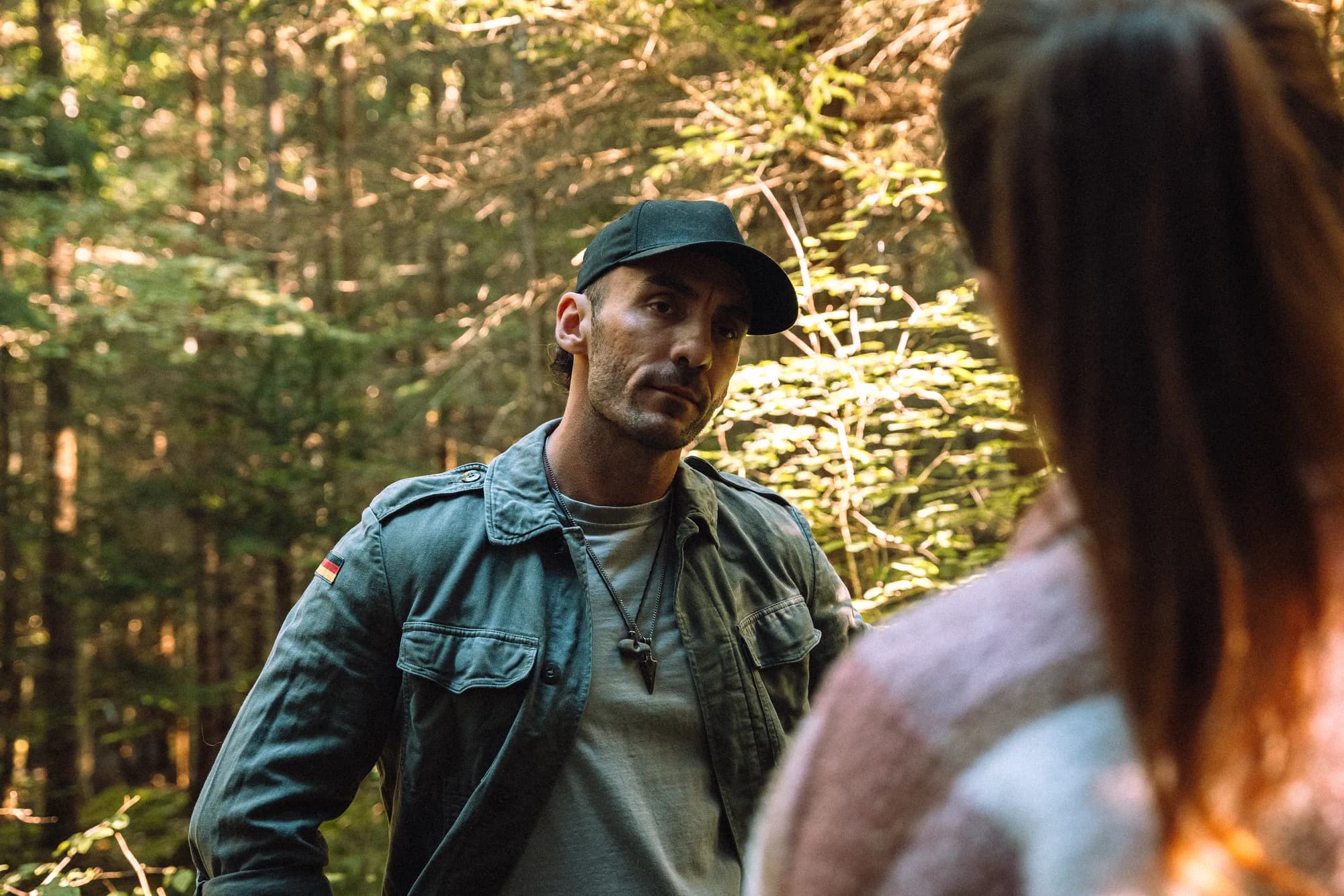Adrian hört einer Gesprächspartnerin im Wald aufmerksam zu